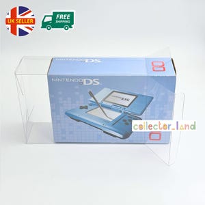 Pode incluir: Um console de jogos Nintendo DS azul na sua caixa original, exibido numa caixa de plástico transparente. A caixa apresenta o logótipo Nintendo DS e uma imagem da consola. Inclui autocolantes "UK Seller" e "Envio Gratuito".