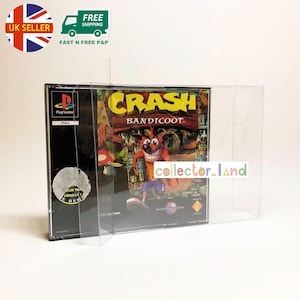 May include: A PlayStation game case for "Crash Bandicoot" in a clear protective sleeve. The game's title and character are visible. The game is a PAL version.
