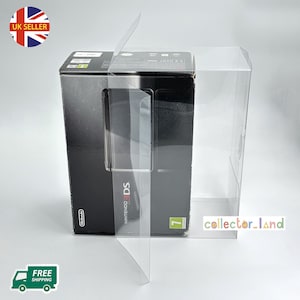 May include: A black Nintendo 3DS game console box inside a clear plastic display case. The box has the Nintendo logo and the text "NINTENDO 3DS". The display case is open, showing the console box.