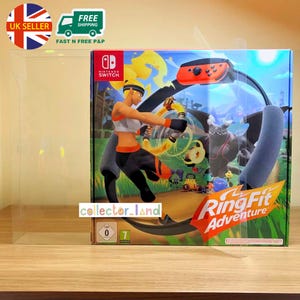 Puede incluir: Una caja del juego Nintendo Switch Ring Fit Adventure. La caja presenta una ilustración dinámica de un personaje haciendo ejercicio con el accesorio Ring-Con. El logotipo del juego se muestra de forma destacada. La caja está en una funda protectora transparente.