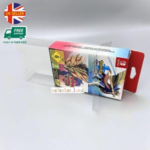 Puede incluir: Un juego de caja de video Pokémon Espada y Escudo en una vitrina de plástico transparente. La caja presenta gráficos coloridos y el texto "Pokemon Sword" y "Pokemon Shield". La vitrina tiene un asa roja.