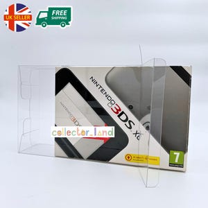 May include: A Nintendo 3DS Xl game console box is displayed inside a clear plastic protective case. The box is white and black with the Nintendo 3DS logo. The text "collector_land" is printed on the box. The UK seller and free shipping logos are visible.