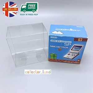 May include: A clear plastic display case next to a Game Boy Advance SP Famicom Color box. The box features a blue background with game graphics and the Nintendo logo. The text "collector_land" is visible.