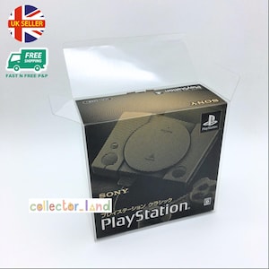 May include: A black and gold PlayStation Classic console box inside a clear plastic case. The box features the PlayStation logo and the word "SONY". The Japanese text is visible. The box is in a clear plastic case.