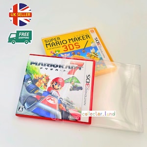 Puede incluir: Dos cajas de juegos de Nintendo 3DS. La caja frontal es para "Mario Kart 7" con Mario en un kart rojo. La otra caja es para "Super Mario Maker 3DS". Ambas cajas están en fundas protectoras transparentes.