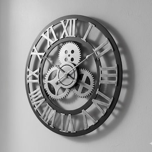 May include: A round, black and silver wall clock with Roman numerals and visible gears. The clock face features a black outer ring with silver Roman numerals and a silver center with three visible gears. The clock hands are silver.