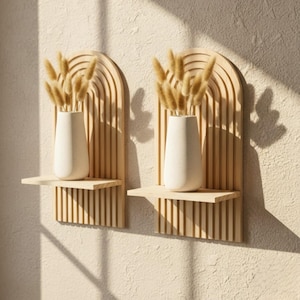 Puede incluir: Dos estanter&iacute;as de pared de madera con dise&ntilde;o arqueado y listones verticales. Cada estanter&iacute;a contiene un jarr&oacute;n blanco lleno de hierba seca de color marr&oacute;n claro. Las estanter&iacute;as est&aacute;n montadas en una pared texturizada blanquecina.