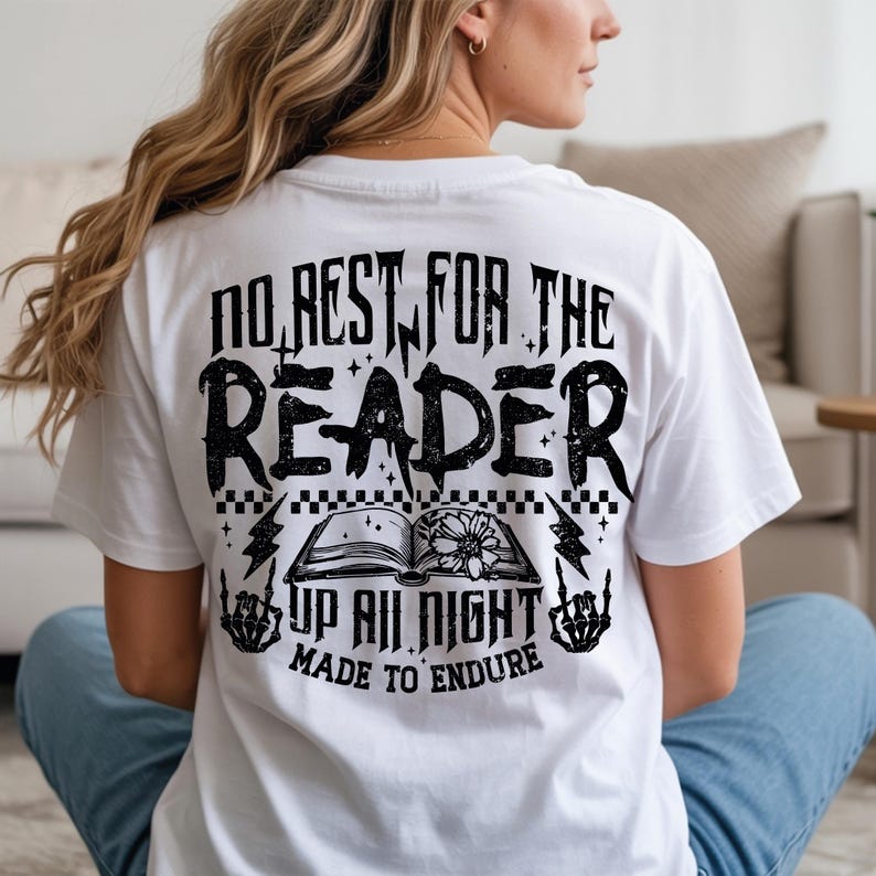 May include: White t-shirt with a black graphic design on the back. The design includes the text "NO REST FOR THE READER" above an open book with a flower, and the phrases "UP ALL NIGHT" and "MADE TO ENDURE".