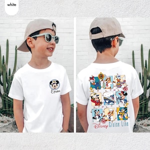 May include: White t-shirt featuring a Mickey Mouse graphic with the name "Ethan" on the front. The back of the shirt displays a colorful Disney Cruise Line design with various Disney characters. The shirt is short-sleeved.