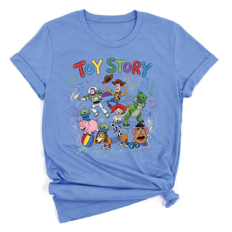 May include: Light blue t-shirt featuring the words "TOY STORY" in colorful letters, with cartoon characters from the movie. The design includes Buzz Lightyear, Woody, Jessie, Rex, and Mr. Potato Head.