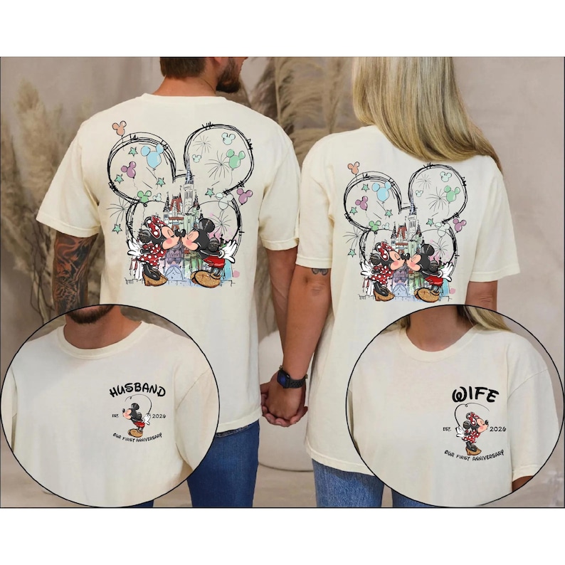 May include: Cream-coloured t-shirts with a Mickey and Minnie Mouse design kissing in front of a castle, with fireworks and a Mickey Mouse head outline. One shirt says "Husband" and the other says "Wife".
