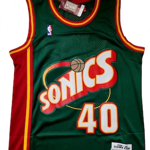 Könnte beinhalten: Grünes Basketballtrikot mit roten und gelben Verzierungen. Das Trikot zeigt das Wort "SONICS" in Weiß mit roten Akzenten, die Nummer "40" und eine Basketballgrafik. Das Trikot hat ein Etikett mit der Aufschrift "Hardwood Classics".