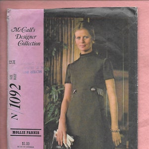 May include: McCall's Designer Collection sewing pattern for a black mock neck dress with short sleeves and a white trim. The pattern number is N/1092 and the size is 12-34 bust.