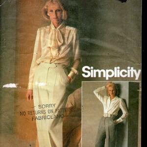 Pode incluir: Um envelope de molde de costura Simplicity 6586 Connoisseur Collection para uma blusa com gola de laço e calças de cintura subida. A embalagem indica o tamanho 14, cintura 71 cm, e ilustrações das peças em creme e cinzento.