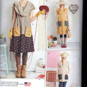 Peut inclure: Patron de couture Simplicity 1080 A présentant trois modèles de robes. Les robes ont des motifs floraux, des poches et différentes longueurs de manches. L'image comprend le texte "dottie angel" et "handcrafted vintage eclectic".