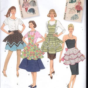 May include: Simplicity sewing pattern 2592 featuring four apron designs. The aprons have various styles, including polka dots, floral prints, and tiered ruffles. The pattern includes sizes A, S, M, and L.