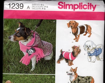 May include: A sewing pattern for dog clothes, Simplicity pattern number 1239. The pattern includes instructions for making a pink hooded coat, a brown football jersey, a pink and white coat, a camouflage coat, and a black and white houndstooth coat.