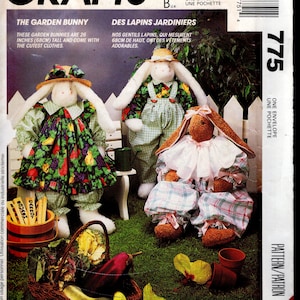 Op de afbeelding: McCall's Crafts patroonhoes met drie pluche tuin konijnen, elk ongeveer 68 cm hoog, gekleed in charmante outfits. De hoes bevat tekst in het Engels en Frans, met een mandje groenten.