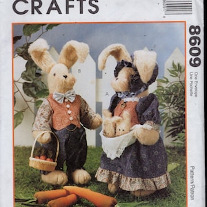 May include: McCall's Crafts sewing pattern featuring two plush bunny figures. One bunny wears a vest and bow tie, the other a dress and bonnet. The pattern includes instructions for making the bunnies and a basket of carrots.