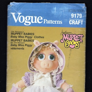 May include: A vintage Vogue sewing pattern for a Miss Piggy doll. The pattern is for a craft project and includes instructions for making a doll with a purple dress, white apron, and lace trim. The pattern number is 9179.
