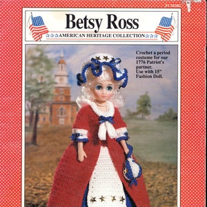 Könnte beinhalten: Puppe in einem rot-weiß-blauen Häkelkostüm, das an Betsy Ross erinnert, mit passendem Häubchen und Handtasche. Die Puppe ist Teil der American Heritage Collection und für eine 38 cm große Modepuppe konzipiert.