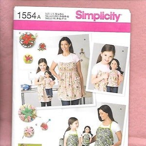 May include: A sewing pattern for a dress and apron for a woman and a girl. The pattern is from Simplicity and the pattern number is 1554A. The dress and apron are both floral patterned.