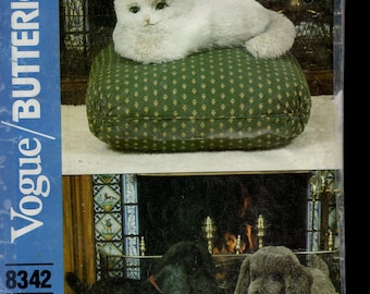 May include: A vintage sewing pattern cover featuring a plush white cat on a green cushion and two dog figures. The cover includes the text "Vogue/Butterick" and the pattern number 8342. The A.S.P.C.A. will benefit from the sales of this pattern.