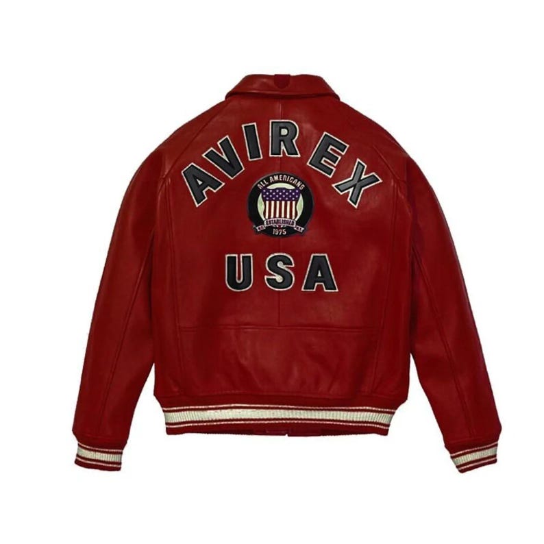 K&ouml;nnte beinhalten: Rote Lederjacke mit dem Wort "AVIREX" &uuml;ber den Schultern. Darunter befindet sich ein Aufn&auml;her mit den Worten "ALL AMERICANS ESTABLISHED 1975" und dem Wort "USA". Die Jacke hat wei&szlig;-rot gestreifte B&uuml;ndchen und Saum.