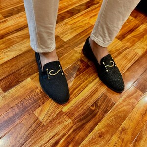 Luxury black formal loafers for men with shimmering texture photographed in elegant indoor fashion styling setup.