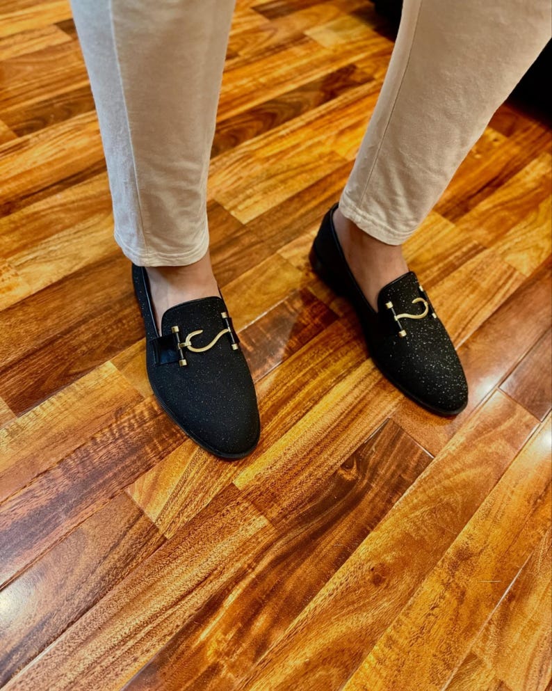 Luxury black formal loafers for men with shimmering texture photographed in elegant indoor fashion styling setup.