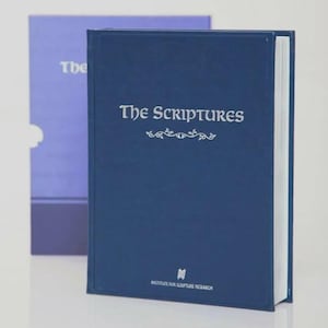 May include: A navy blue book titled "The Scriptures" with silver lettering and decorative flourishes. The book is in front of a light purple book. The bottom of the navy blue book has the text "Institute for Scripture Research".