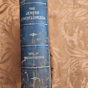Puede incluir: Un libro antiguo, encuadernado en cuero azul, titulado "The Jewish Encyclopedia, Vol. IV". El lomo del libro presenta letras blancas y detalles florales decorativos. El nombre del editor, Funk & Wagnalls Company, está impreso en la parte inferior.
