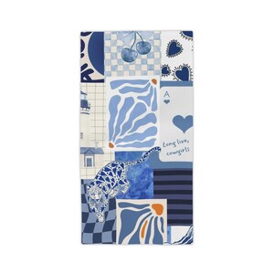 May include: A rectangular, blue and white patterned textile featuring various designs. The design includes a leopard, cherries, hearts, and the text "Long live, cowgirls." The textile has a patchwork aesthetic with a mix of patterns.