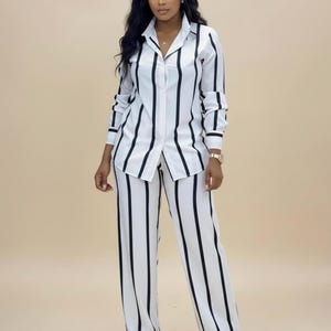 Peut inclure: Un ensemble deux pièces à rayures blanches et noires. L'ensemble comprend une chemise boutonnée à col et un pantalon large. Les rayures verticales sont noires sur fond blanc. La chemise à manches longues a des rayures noires aux poignets.