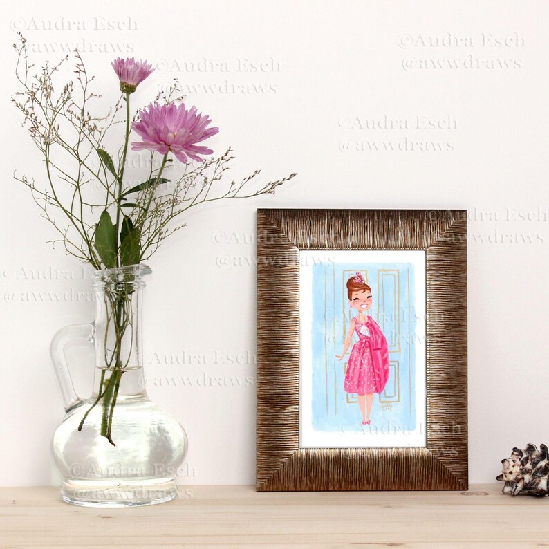 May include: A framed illustration of a woman in a pink dress standing in a doorway. The woman is wearing a crown and has a smile on her face. The illustration is done in a watercolor style.