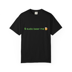 Peut inclure: T-shirt noir avec l'inscription verte "$ sudo beer me" et une icône de chope de bière. Le t-shirt est de style col rond et à manches courtes.