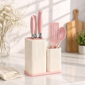 May include: A kitchen knife set with a pink handle and silver blades, displayed in a cream-colored block. A matching pink spatula and spoon are in a separate container. The set sits on a pink tray, with a cutting board in the background.