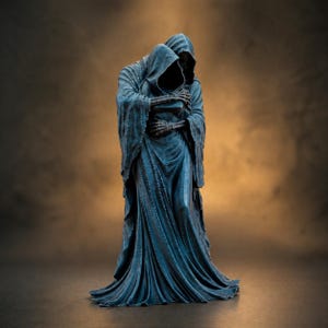 Peut inclure: Statue bleu foncé représentant deux figures encapuchonnées s'embrassant. Les figures sont vêtues de robes fluides, avec des mains squelettiques jointes. La statue a une surface texturée sur fond marron.