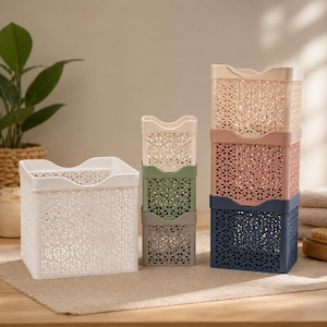 May include: A selection of decorative storage crates in various colours, including white, green, grey, pink, and navy blue. The crates have a geometric pattern and are stacked or placed individually. Ideal for organising items.