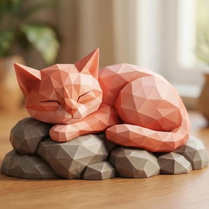 Peut inclure: Une sculpture de chat géométrique pêche reposant sur une base en pierre grise. Le chat est en position de sommeil, les yeux fermés. La sculpture a un design polygonal moderne et convient à la décoration intérieure.