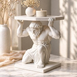 May include: A white sculpture of Atlas, a figure from Greek mythology, kneeling and supporting a hexagonal tabletop. The tabletop holds a small white vase, a candle, and a smaller vase with dried flowers. The sculpture is a decorative accent piece.