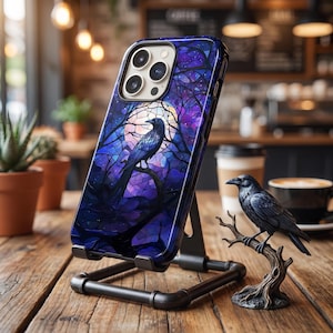 May include: A smartphone case featuring a stained glass style design of a black raven perched on a branch against a large, glowing full moon. The background consists of deep blue and purple hues with intricate tree branch silhouettes throughout.