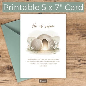 Könnte beinhalten: Eine 5 x 7 Zoll große, bedruckbare Karte mit dem Text "He is risen" und einer Aquarellillustration eines leeren Grabes. Die Karte enthält einen Bibelvers aus Johannes 20:29. Ein Umschlag ist links sichtbar.