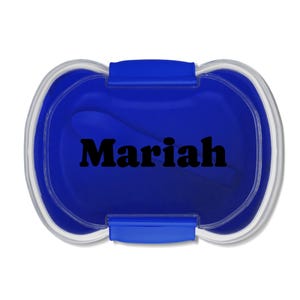 Könnte beinhalten: Ein blauer Behälter mit einem transparenten Rand und einem blauen Verschluss. Das Wort "Mariah" ist schwarz über die Mitte des Behälters gedruckt. Der Behälter ist oval geformt.