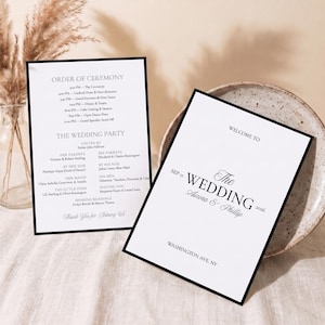 May include: Two white wedding program cards with black borders and black text. One card displays the order of ceremony and wedding party names. The other card features the text Welcome to the Wedding of Aurora & Phillip, Sep 11, 2026, Washington Ave, NY.