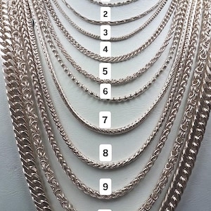 May include: A collection of eleven silver-toned metal chains displayed on a white neck form. Each chain features a distinct link style, numbered one through eleven, ranging from thin, delicate designs to thicker, more substantial braided and curb links.