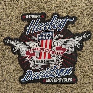 May include: Black Harley-Davidson patch with white wings, red and white stripes, and the text "Genuine Harley-Davidson Motorcycles." The patch features the number "1" and the year "1903."