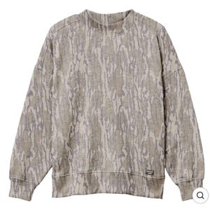 May include: A long-sleeve sweatshirt featuring a light brown and grey tree bark camouflage pattern. The garment has a mock neck collar, dropped shoulders, and a small rectangular black label with the white text Mossy Oak at the bottom hem.