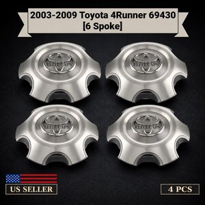 May include: A set of four silver-colored wheel center caps for 2003-2009 Toyota 4Runner 69430 6 spoke wheels. Each cap features a raised Toyota emblem in the center with the text Elite Caps printed below it. The text 4 PCS and US SELLER are visible.