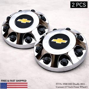 May include: Two chrome hubcaps with a black center featuring a yellow Chevrolet logo. Each hubcap has black lug nuts around the perimeter. The text "2 PCS" is in the upper right corner.